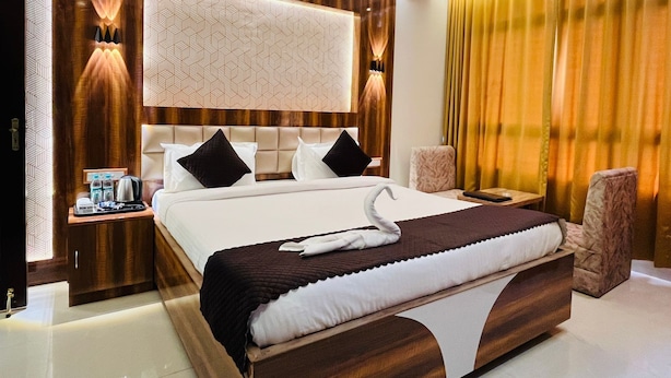 A modern bedroom with a large bed, a wooden headboard, a nightstand with a lamp, and a window with curtains. - Riverdale Homestay, Diamond Harbour -WB Govt Reg Gold Category (Diamond Harbour)