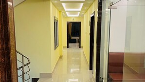 A modern hallway with a glass partition, a staircase, and a black rug on the floor. - Riverdale Homestay, Diamond Harbour -WB Govt Reg Gold Category (Diamond Harbour)