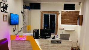 A hotel reception area with a reception desk, a television, a sofa, and a glass table. - Riverdale Homestay, Diamond Harbour -WB Govt Reg Gold Category (Diamond Harbour)