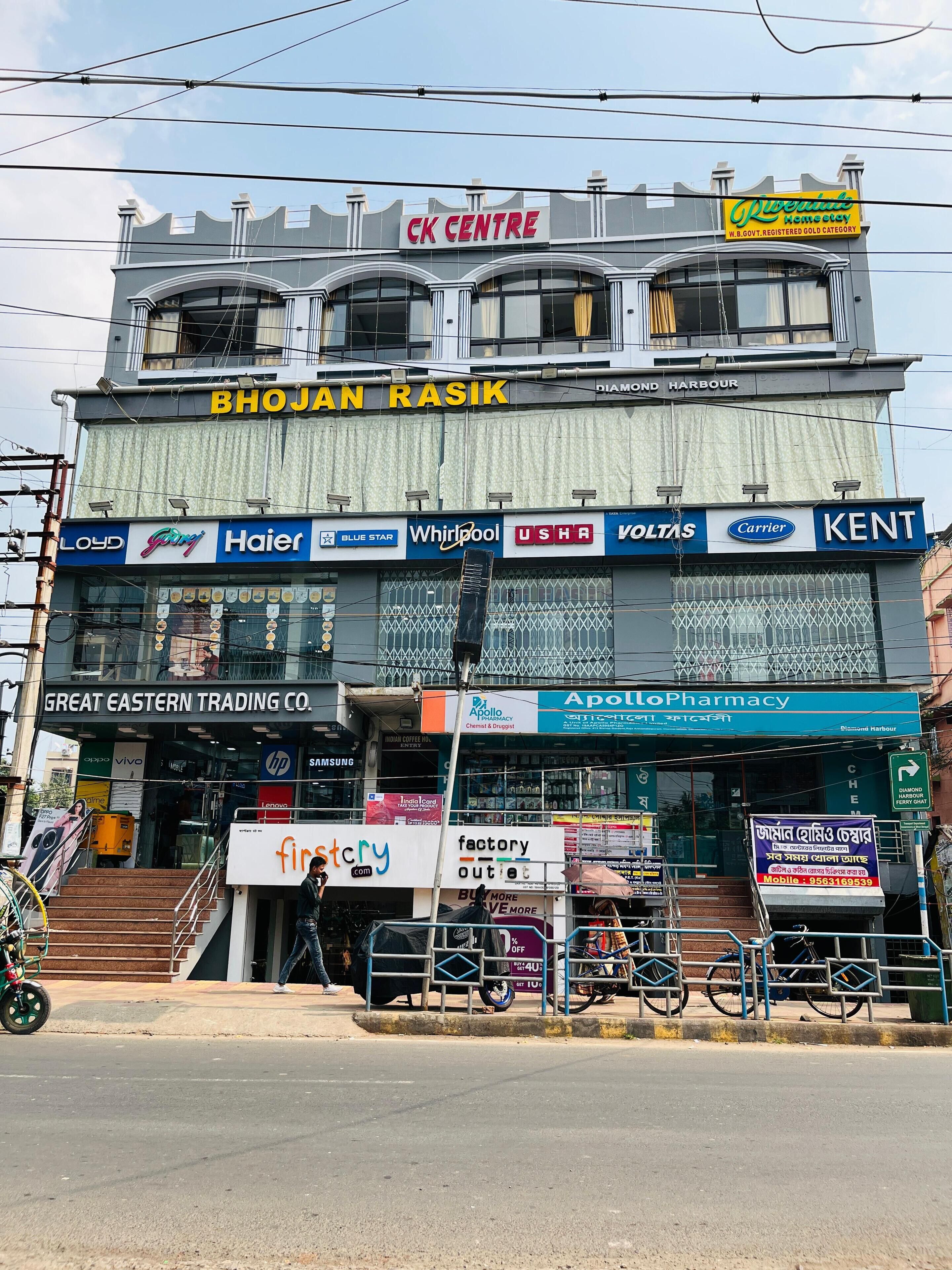 Un edificio comercial de varios pisos con diversas tiendas en la planta baja, incluyendo una farmacia y una empresa comercial.