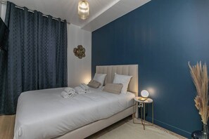 Une chambre à coucher avec un grand lit, une table de chevet avec une lampe et un élément décoratif mural.