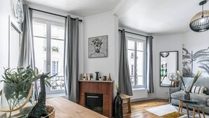 Una sala de estar moderna con chimenea, ventanas amplias y un sofá gris.