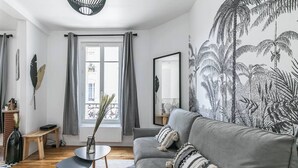 Una sala de estar con un sofá gris, una mesa de centro de madera y un ventanal con cortinas grises.