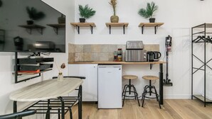 A compact kitchen with a refrigerator, microwave, and coffee maker. There are three stools and a small table. - Splendide Appart 2P- Popincourt Paris centre (Paris)