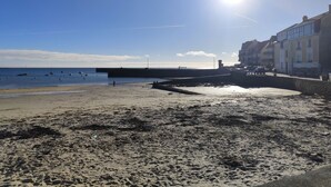 A beach with a pier, buildings, and boats.