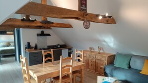 A cozy loft-style living space with a dining area, kitchenette, and a sofa.