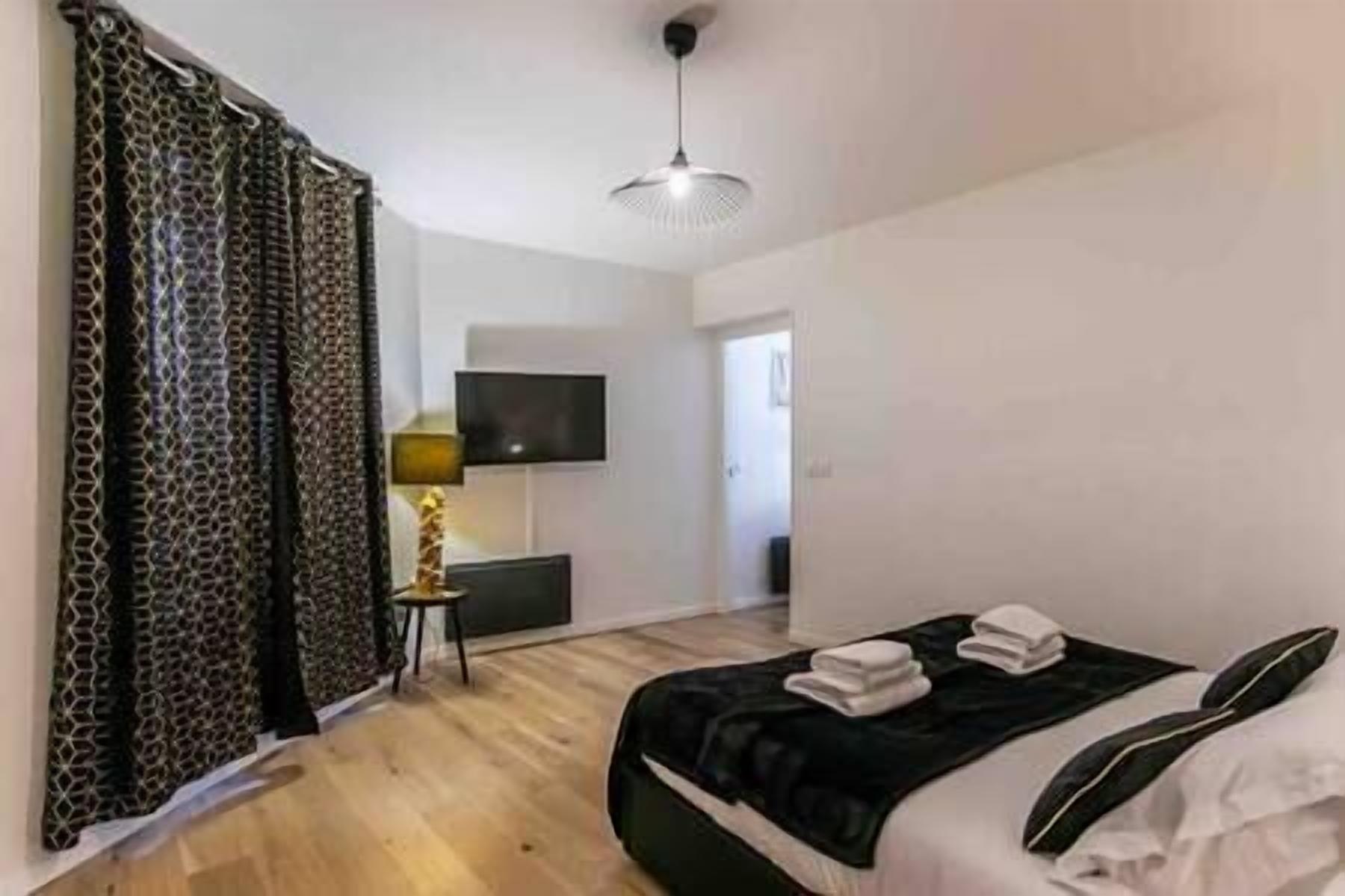 A bedroom with a bed, a TV mounted on the wall, and a door leading to another room.