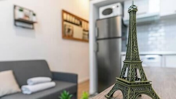 A model of the Eiffel Tower on a wooden table in a living room with a grey sofa and a small plant. - Splendid 8-room apartment near Bercy (Paris)