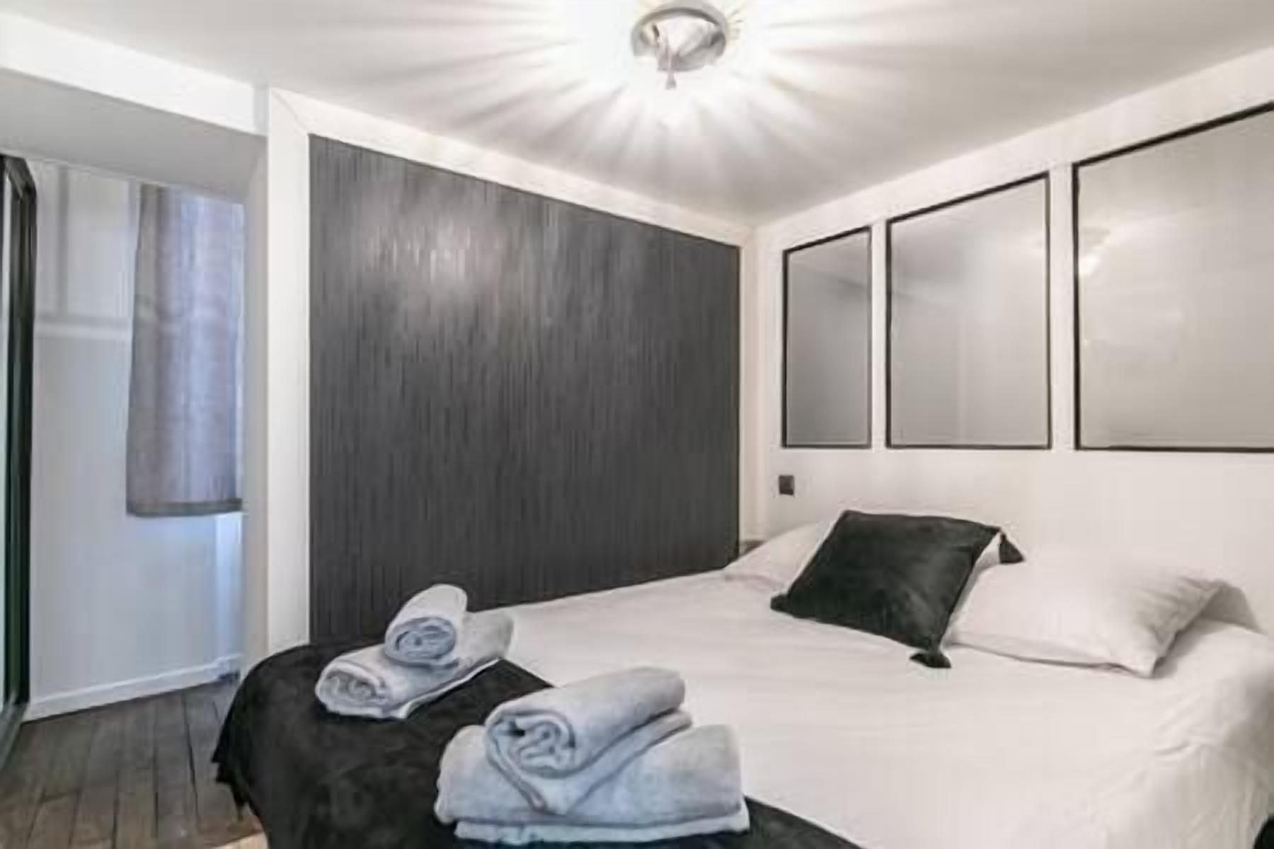Una habitación de hotel moderna con una cama grande, un cabecero de madera oscura y tres espejos a los lados.