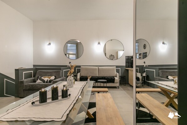 Un salon moderne avec un canapé, une table basse et des objets de décoration. Deux miroirs ronds sont accrochés au mur, et un banc en bois est également présent.