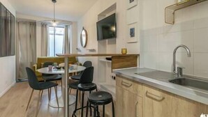 Une cuisine compacte comprenant un coin repas, un évier et un téléviseur fixé au mur.