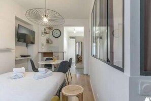Une chambre d’hôtel avec un lit, un bureau, une chaise, une petite table, une télévision et une fenêtre.