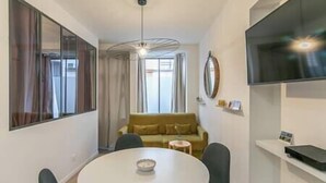 Un salon moderne avec une table ronde, un canapé et un téléviseur fixé au mur.