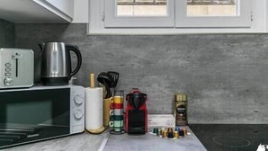 A kitchen with a microwave, kettle, and various kitchen utensils.