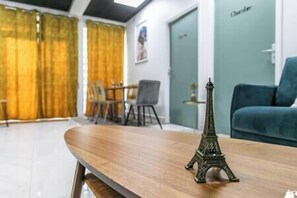 A room with a wooden table, a small Eiffel Tower model, a teal sofa, and a door labeled "Charter". - MBA Splendide Appart - Montreuil Centre (Montreuil)