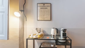 A small table with a coffee maker, a teapot, and a tray with cups and utensils. A framed document is hung on the wall above the table. - Guesthouse Volta38 in the center of Como! (Como)