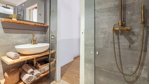 A modern bathroom with a white sink, gold fixtures, and a glass shower enclosure. - Guesthouse Volta38 in the center of Como! (Como)