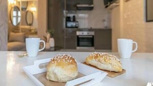 A modern kitchen with a microwave, oven, and a coffee machine. There are two white cups on the counter.