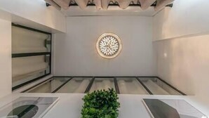 A modern bathroom with a central circular light fixture, a plant on the counter, and a glass shower enclosure. - MBA Splendide Appart 3 - Proche Musée du Louvre (Paris)