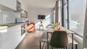 A modern kitchen with a dining area, large windows, and a flat-screen TV. - MBA - Fontenay - Splendide Appart Proche Vincennes (Fontenay-sous-Bois)