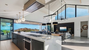 A modern kitchen with a large island, built-in oven, and a dining area with a view of the ocean.