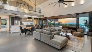 A spacious living area with a large sectional sofa, a dining table, and a kitchen in the background.