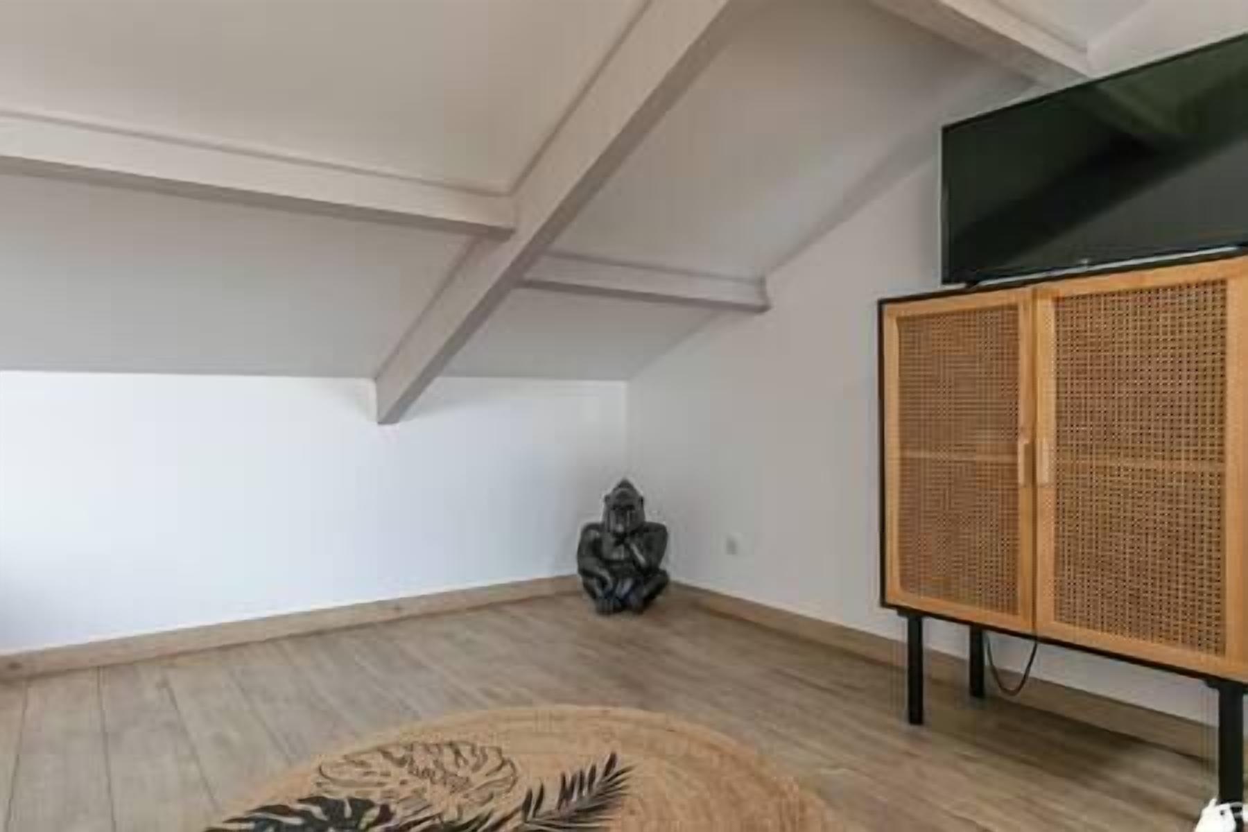 Een kamer met een hoog plafond, een houten kast en een televisie.