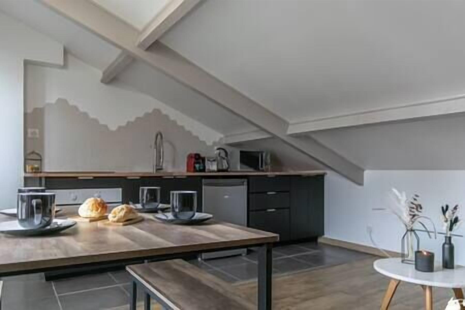 Une cuisine moderne avec une table en bois, un banc et une petite table ronde sur laquelle est posée une bougie.