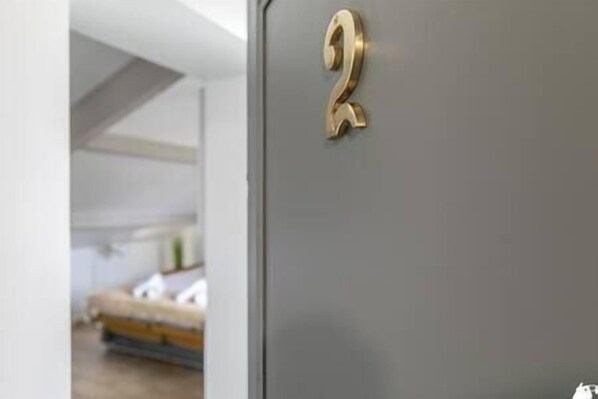 A room with a grey door and a golden number '2' sign. - MBA Splendide Appart -Montreuil 2-Proche Vincennes (Montreuil)