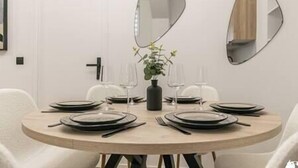 A round dining table with a central vase of flowers, surrounded by chairs and set with plates, glasses, and cutlery. - MBA - Felix Faure Luxury Appart proche Tour Eiffel (Paris)