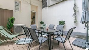 A patio with a glass table and chairs, surrounded by potted plants and a small outdoor seating area. - MBA - Felix Faure Luxury Appart proche Tour Eiffel (Paris)