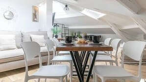 Ein Essbereich mit Holztisch, weißen Stühlen und einem modernen Deckenbau.