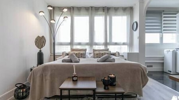 A modern bedroom with a bed, bedside table, lamp, and a view of the outside. - MBA - Splendide Appart Proche Château Vincennes (Vincennes)