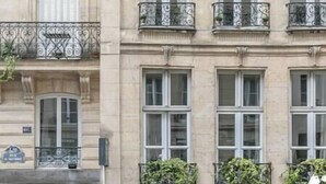 Un immeuble à plusieurs étages de style architectural classique, caractérisé par des balcons en fer forgé richement décorés et de nombreuses fenêtres.