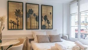 Une chambre d’hôtel avec un lit, une chaise et trois œuvres d’art encadrées accrochées au mur.