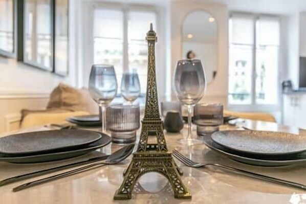 Une table à manger agrémentée d’une petite réplique de la Tour Eiffel en guise de centre de table, de verres à vin et de couverts.