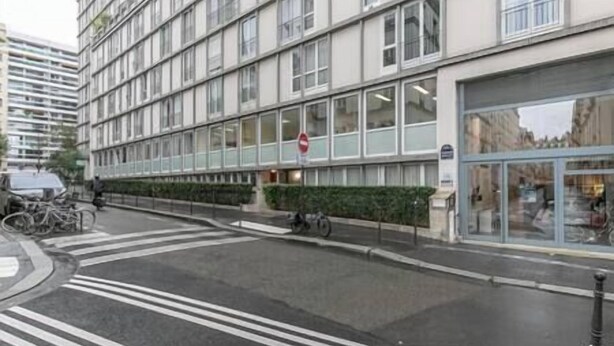 En bygning med flere etager i moderne arkitektur, med store vinduer og en glasindgang.