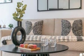 A round table with a black base, a vase with green leaves, and a stack of colorful macarons.