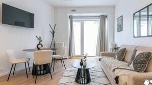 A modern living room with a round coffee table, a sofa, and a dining area with chairs.