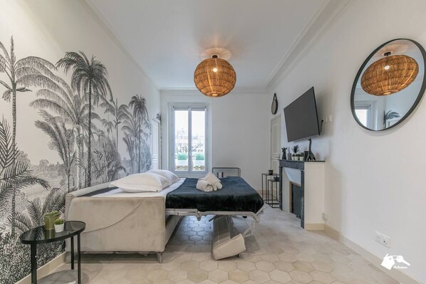 A bedroom with a bed, a TV, a mirror, and a wall mural.