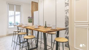 Un espace repas moderne avec une table en bois, six tabourets et une pièce décorative représentant la Tour Eiffel.