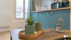 Una cocina con armarios azul verdoso, una cafetera y una planta pequeña sobre una bandeja de madera.