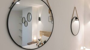 Un dormitorio con cama, mesita de noche, lámpara y espejos en la pared.
