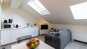 A modern apartment with a kitchen, dining area, and living space, featuring skylights and a flat-screen TV. - notaMi - Bright Attic M4 - 2 Bedrooms (Milan)