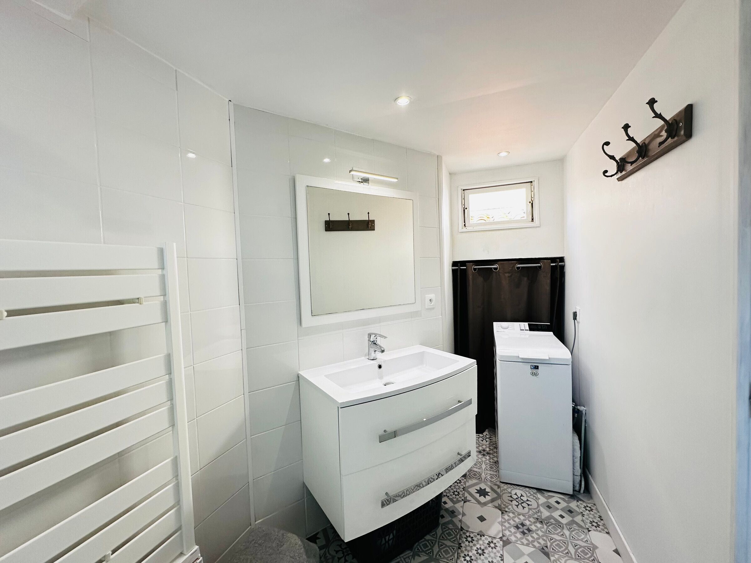 Ein modernes Badezimmer mit einem weißen Waschtisch, einem Spiegel, einem kleinen Waschbecken und einer Toilette.