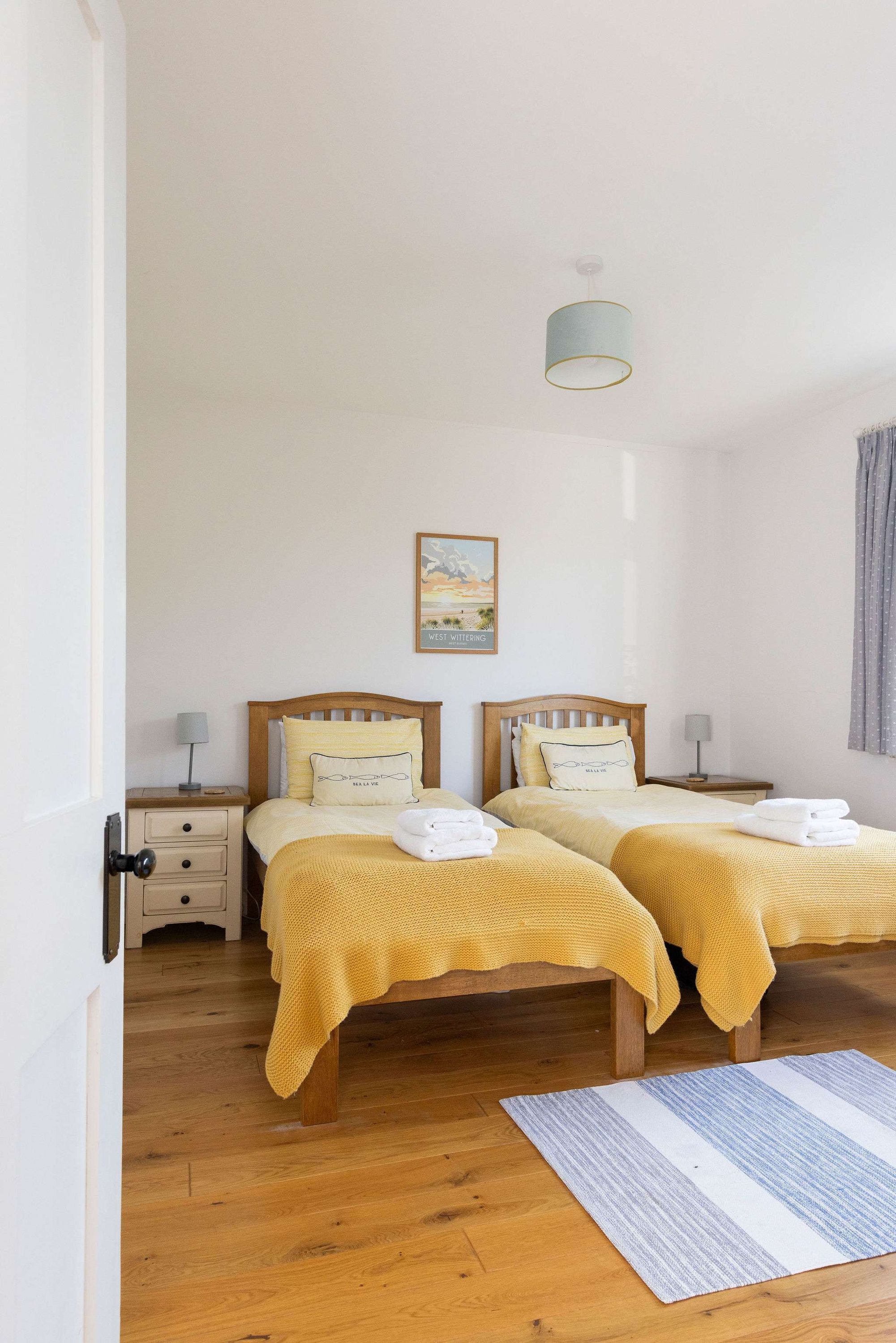 A double room with two beds, wooden headboards, and a single nightstand with a lamp.