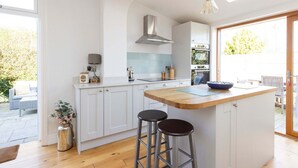Una cocina moderna con armarios blancos, una isla de madera y un tragaluz.