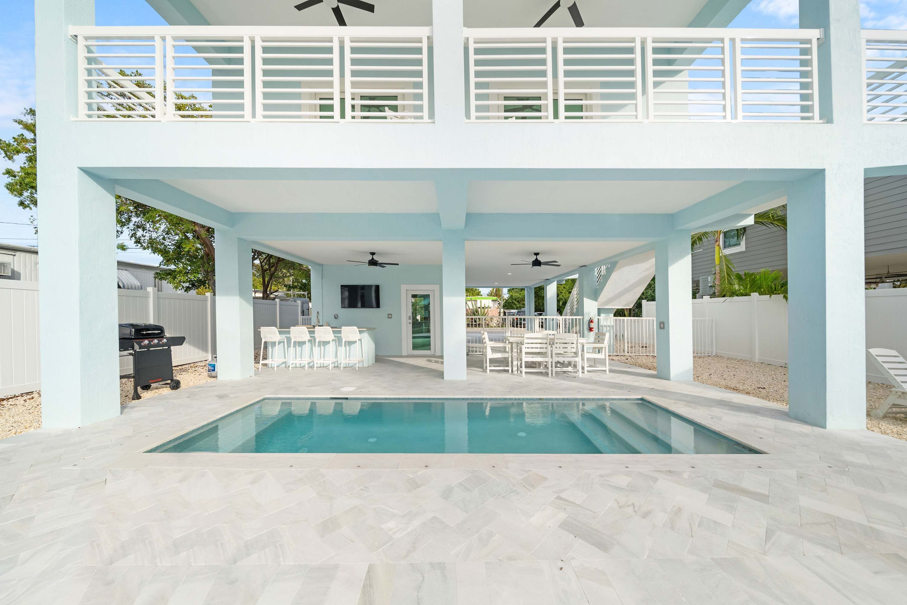 A two-story house with a swimming pool, outdoor seating, and a barbecue area.