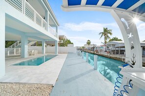 Un espace piscine avec une piscine à l’eau d’un bleu limpide, un coin salon abrité et une vue sur les bâtiments environnants.