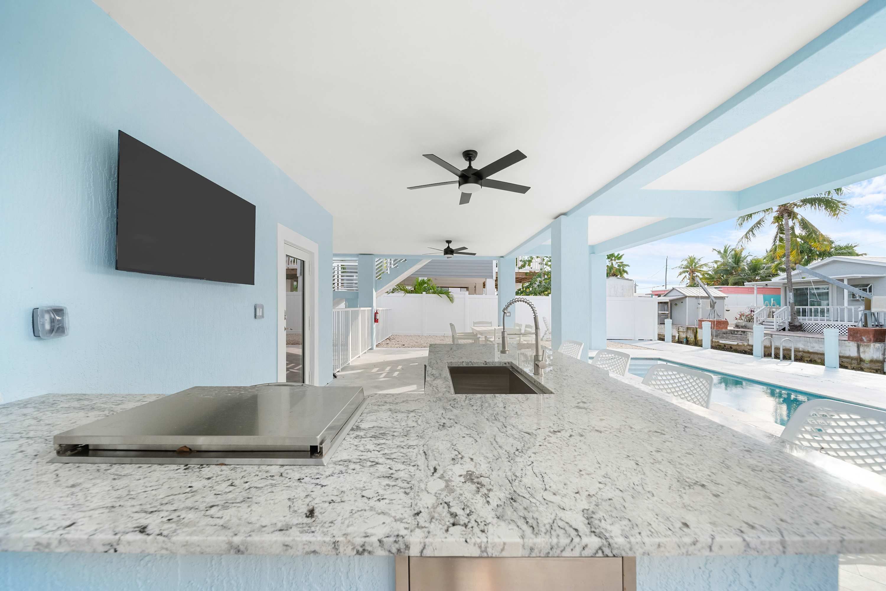 A modern kitchen with marble countertops, a built-in sink, and a ceiling fan.